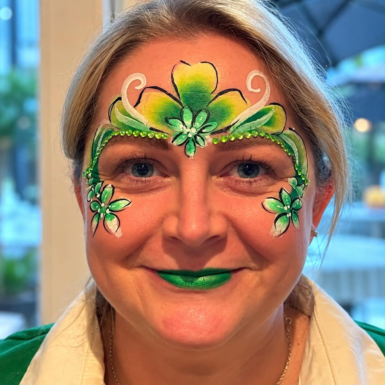 Green floral face painting on an adult