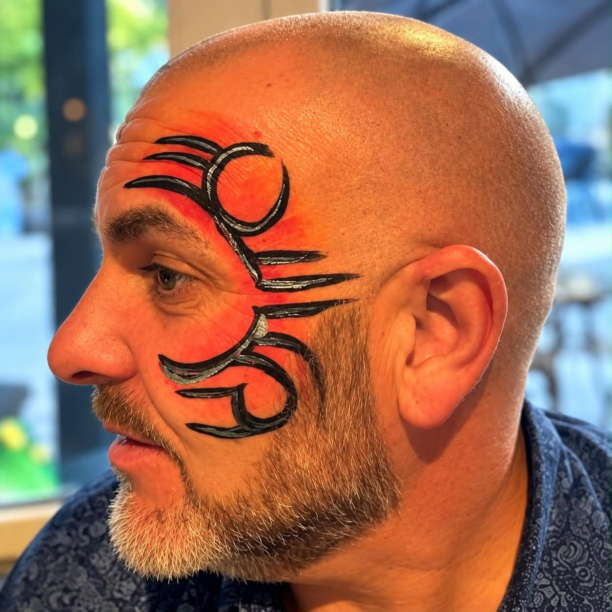 Red and black face painting design for an adult